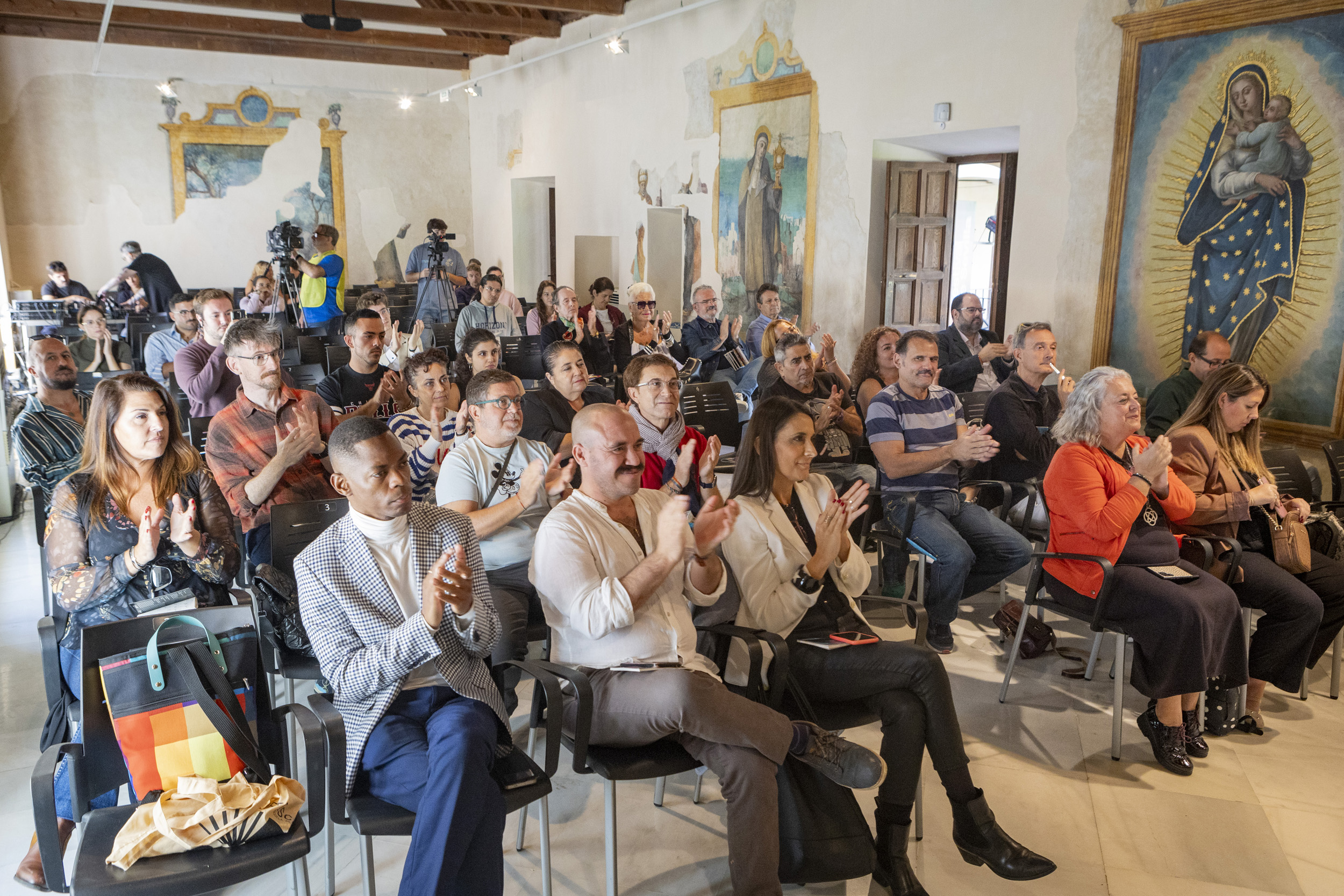 Asistentes a la Rueda de Prensa sentados y aplaudiendo.